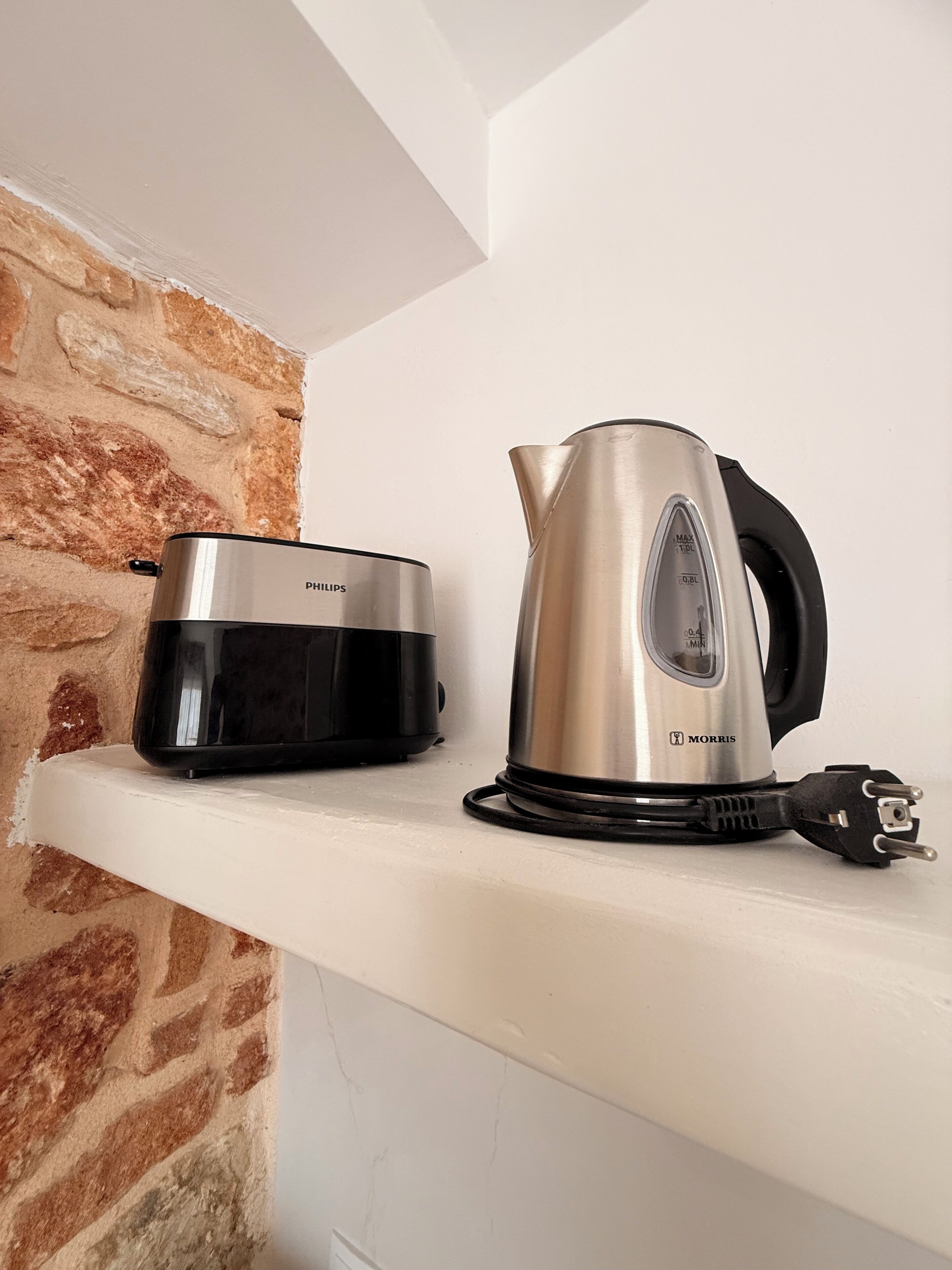 A kitchen with a Philips slow cooker and a Morris electric kettle on a white shelf.