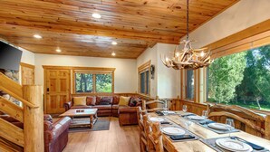 Un intérieur en bois comprenant un coin repas, un ensemble de canapés et un escalier.