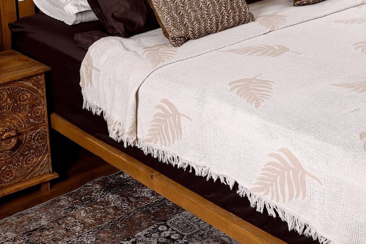 Una cama bien hecha con almohadas estampadas, un cabecero de madera y dos cuadros en la pared.