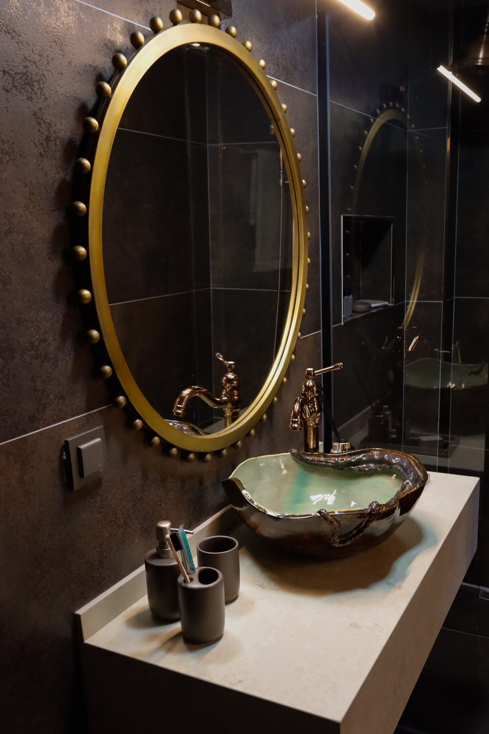 Une salle de bain dotée d’un grand miroir, d’un lavabo avec un receveur original et d’un robinet.