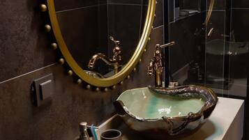 Une salle de bain dotée d’un grand miroir, d’un lavabo avec un receveur original et d’un robinet.