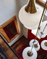 A staircase with a red carpet, a wooden frame, and a brass pendant light.