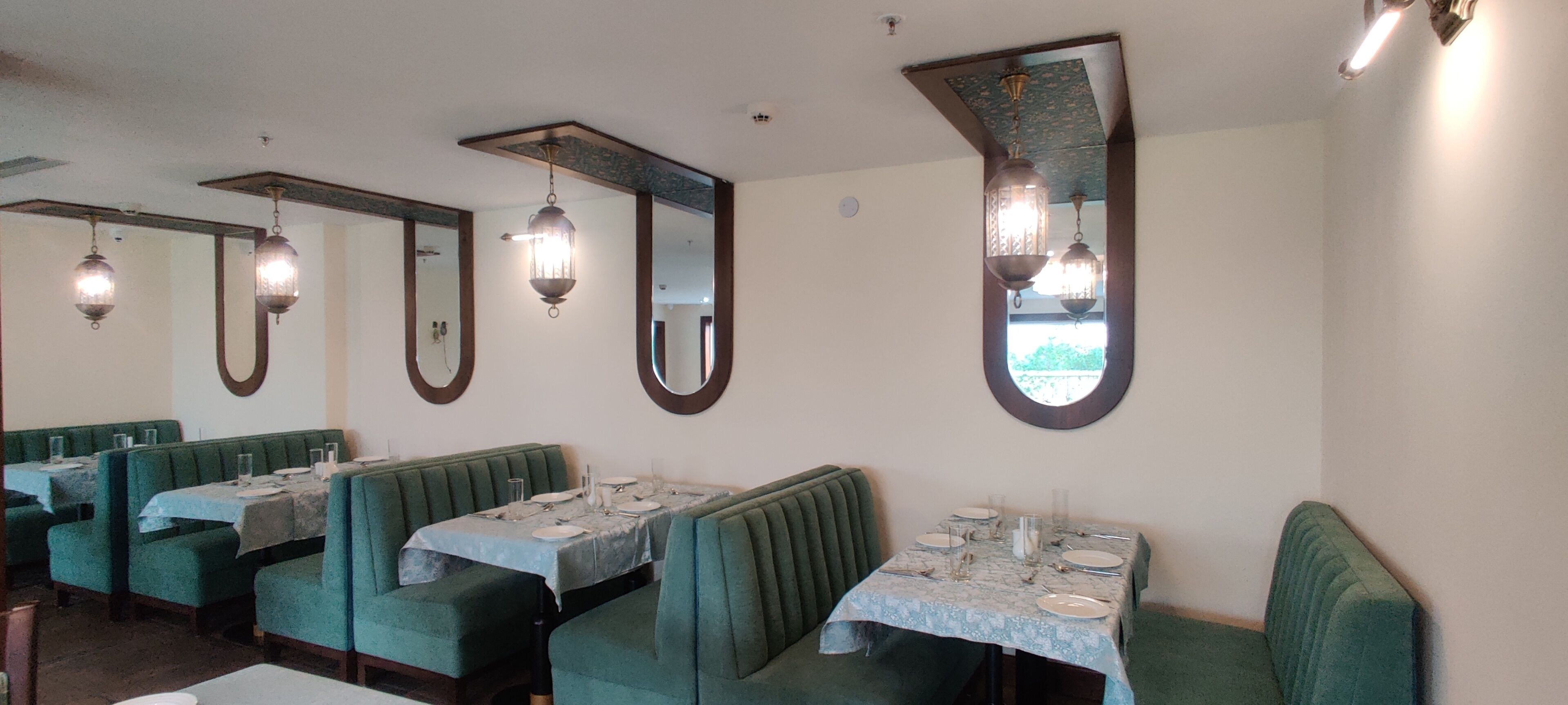A restaurant with booths and tables, each set with plates, glasses, and cutlery.