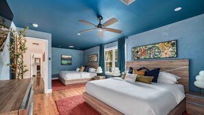 A bedroom with a large bed, two smaller beds, a ceiling fan, and artwork on the walls. - Luxury Poconos Estate*Golf Sim*Pickleball*Sauna (Long Pond)