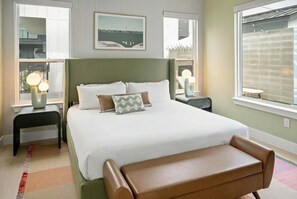 A neatly arranged bedroom with a large bed, bedside tables, and a bench.
