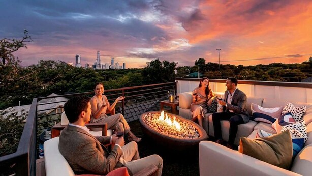 Une terrasse sur le toit, dotée d’un foyer, de sièges et offrant une vue sur le panorama urbain.