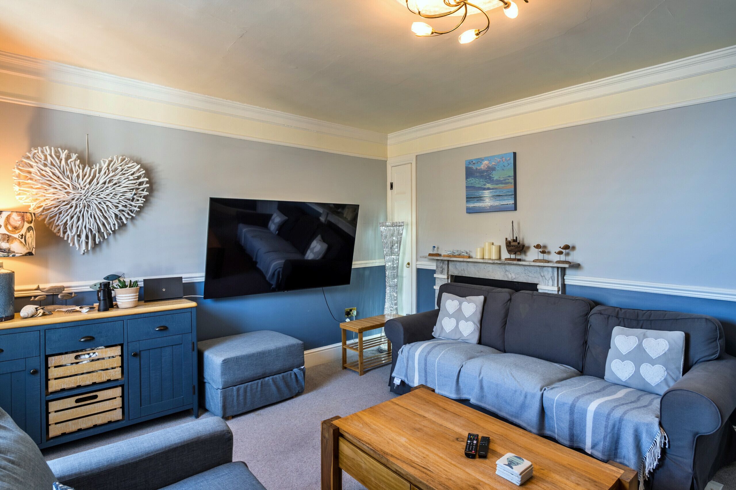 A living room with a TV, sofa, coffee table, and a decorative wall piece.