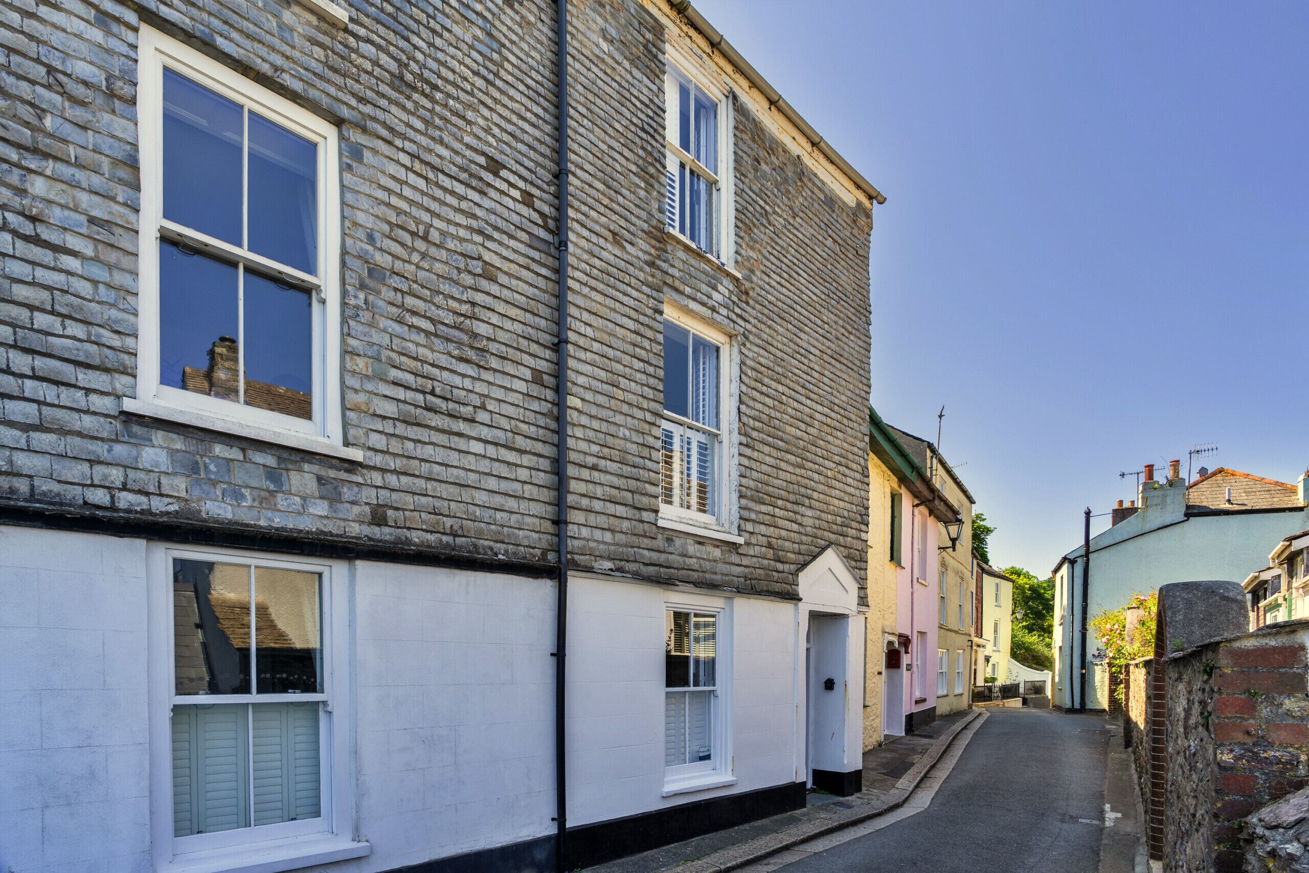 A narrow street with traditional brick buildings, white window frames, and a clear sky.