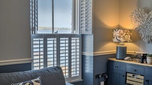 Ein Zimmer mit einem großen Fenster, einem dunkelblauen Schrank und einem Wanddekor.