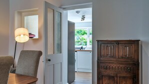 A hallway with a wooden cabinet, a door leading to a kitchen, and a lamp. - Roselric (Kingsand)
