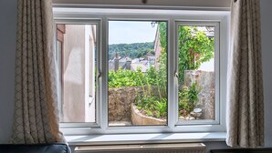 A room with a large window overlooking a garden and a view of buildings. - Roselric (Kingsand)