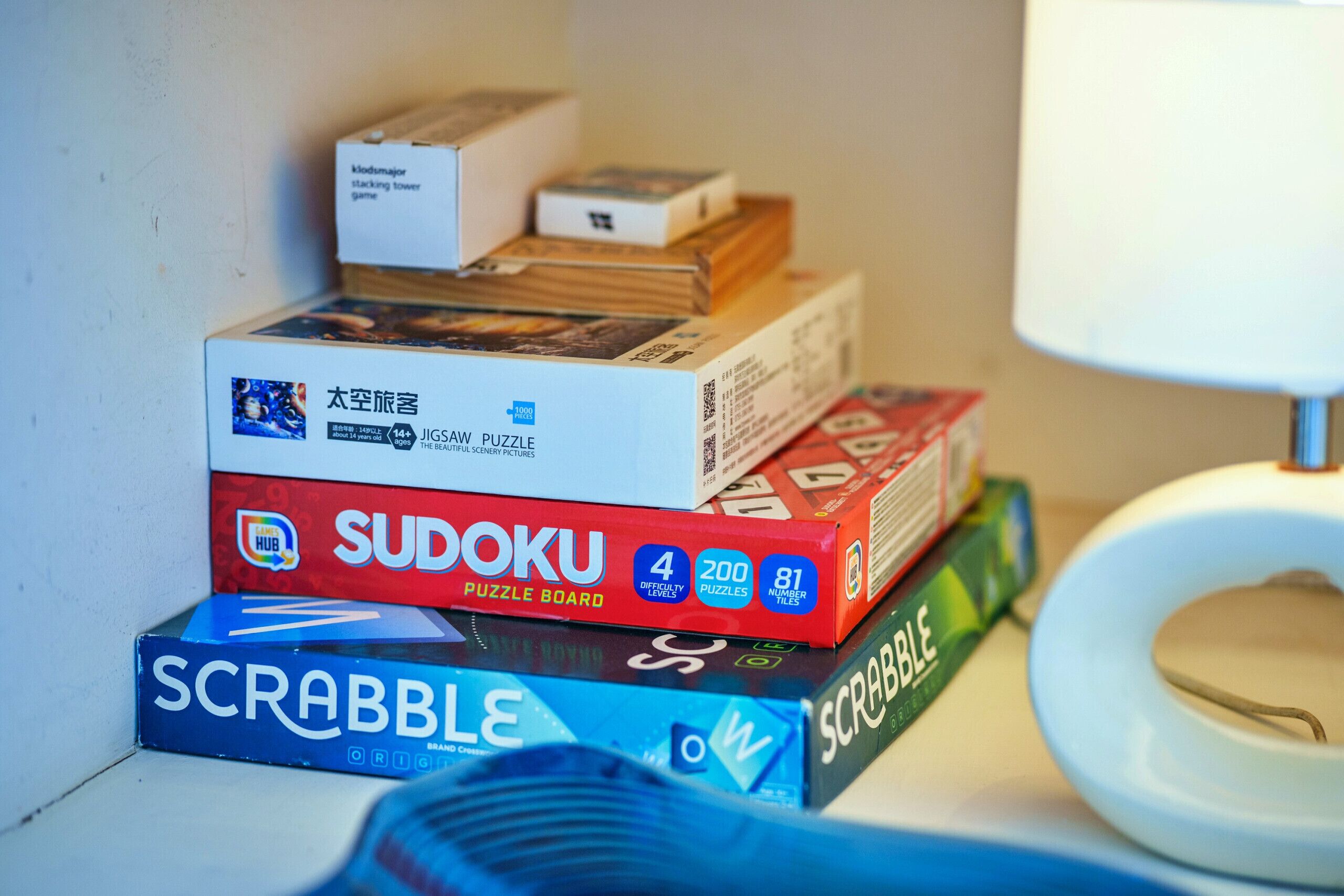 Ein Stapel Brettspiele, darunter Sudoku, Scrabble und Puzzlespiele.