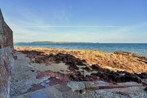 Eine felsige Küstenlinie mit freiem Blick auf das Meer und das entfernte Land.