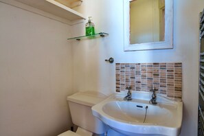 Ein Badezimmer mit einem weißen Waschbecken, einer Toilette und einem grünen Seifenspender auf einem Glastisch.