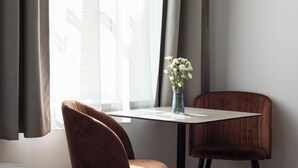Una habitación de hotel con una cama, una mesa con un florero y dos sillas.
