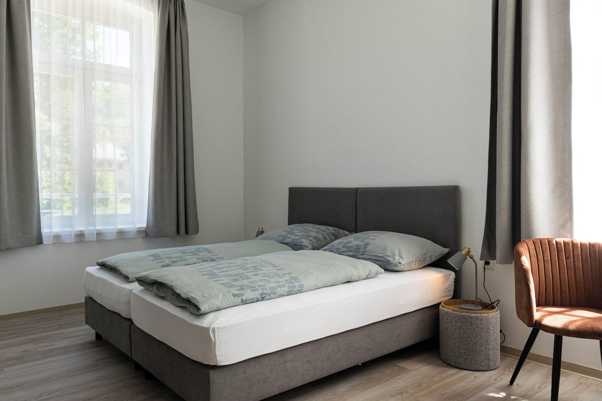 A modern bedroom with a bed, a chair, and a bedside table.