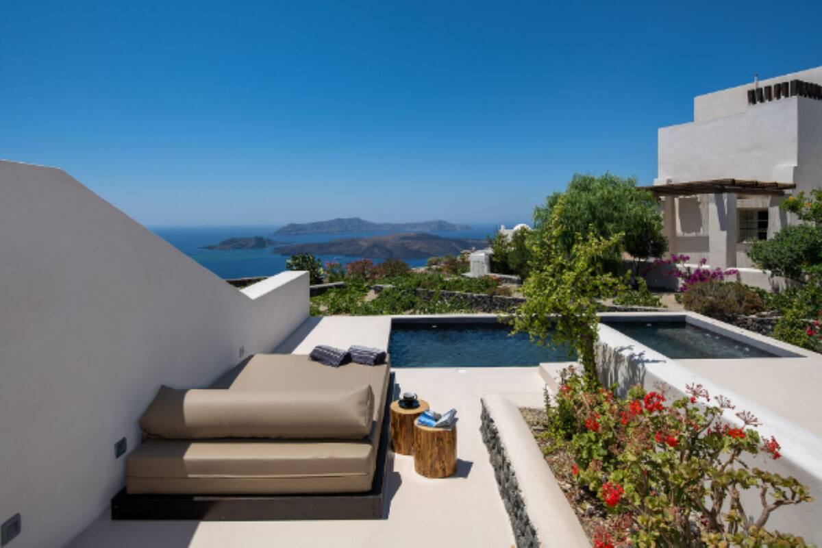 A rooftop terrace with a pool, outdoor seating, and a view of the sea and mountains.