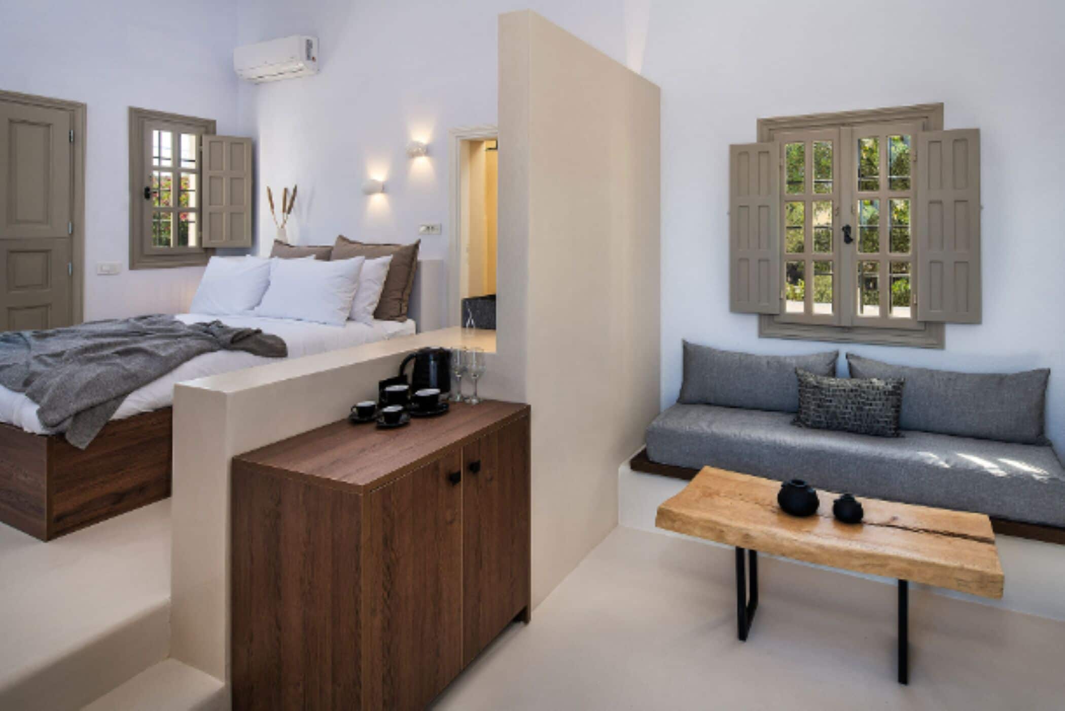A bedroom with a bed, a wooden nightstand, a sofa, and a table.