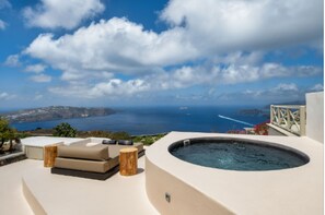 A rooftop terrace with a hot tub, outdoor seating, and a view of the sea and distant islands. - Santo Blue Santorini  (Santorini)