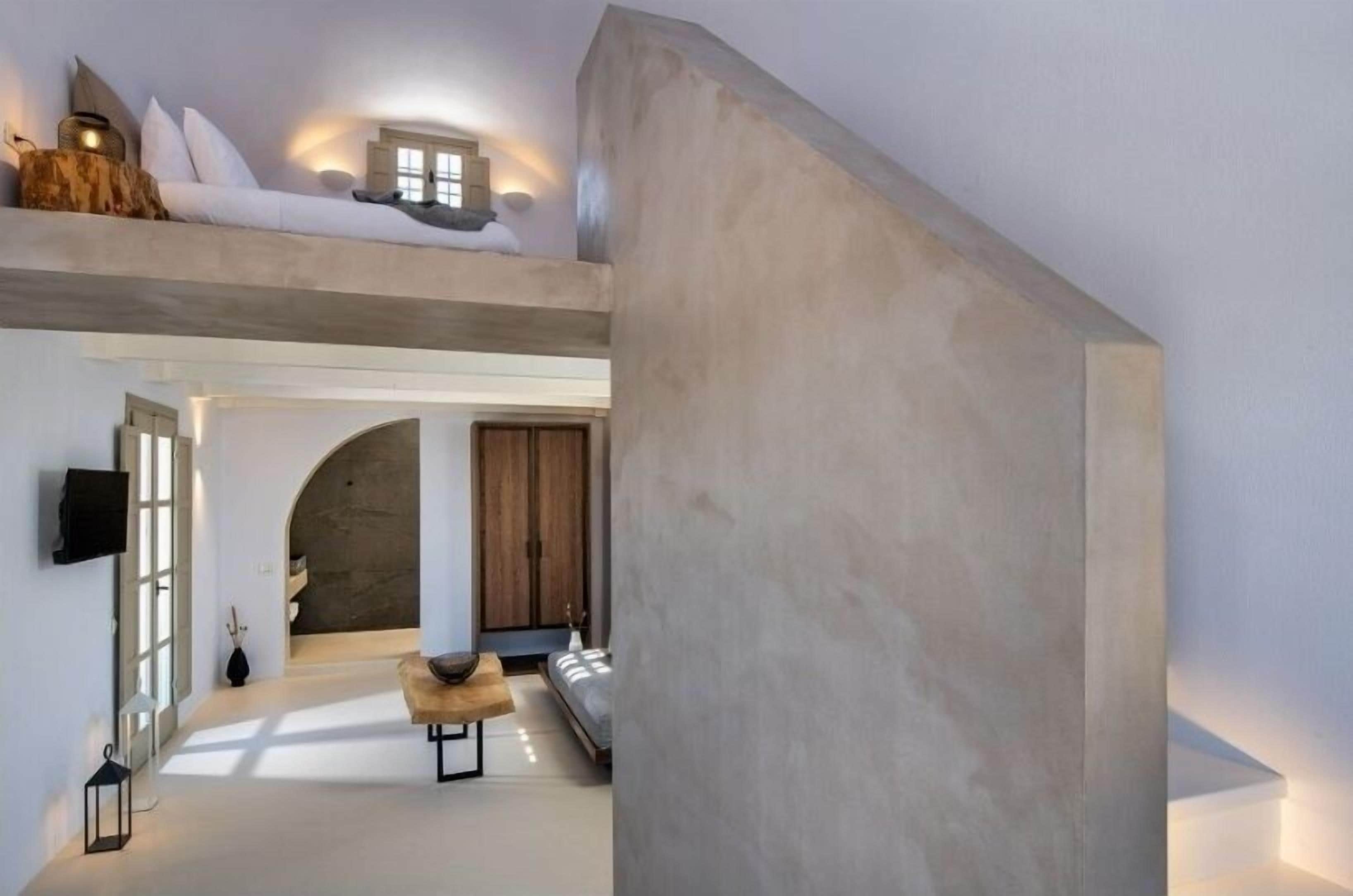 A modern interior with a high ceiling, a loft area with a sofa, a wooden bench, and a staircase.