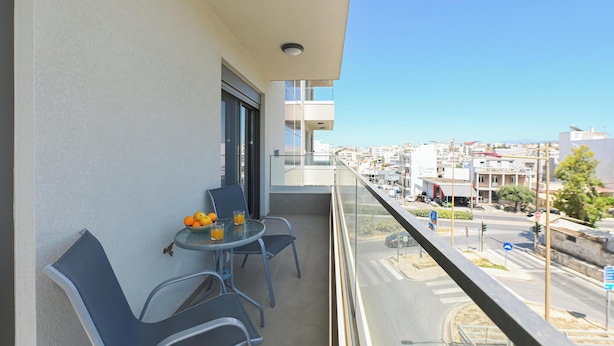 Een balkon met een tafel, stoelen en een schaal fruit.