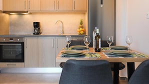 Een moderne keuken met houten kastjes, een roestvrijstalen koelkast en een eettafel gedekt met borden, glazen en een fles.