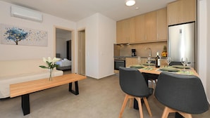 Een moderne keuken met houten kastjes, een roestvrijstalen koelkast, en een eethoek met een houten tafel en stoelen.