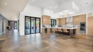 Eine moderne Küche mit einer großen Kochinsel, integrierten Geräten und einem großzügigen Grundriss.