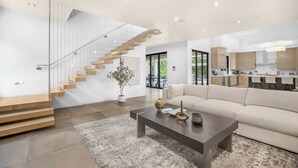 Ein modernes Interieur mit Treppe, Wohnbereich mit Sofa, Couchtisch und Küchenzeile.