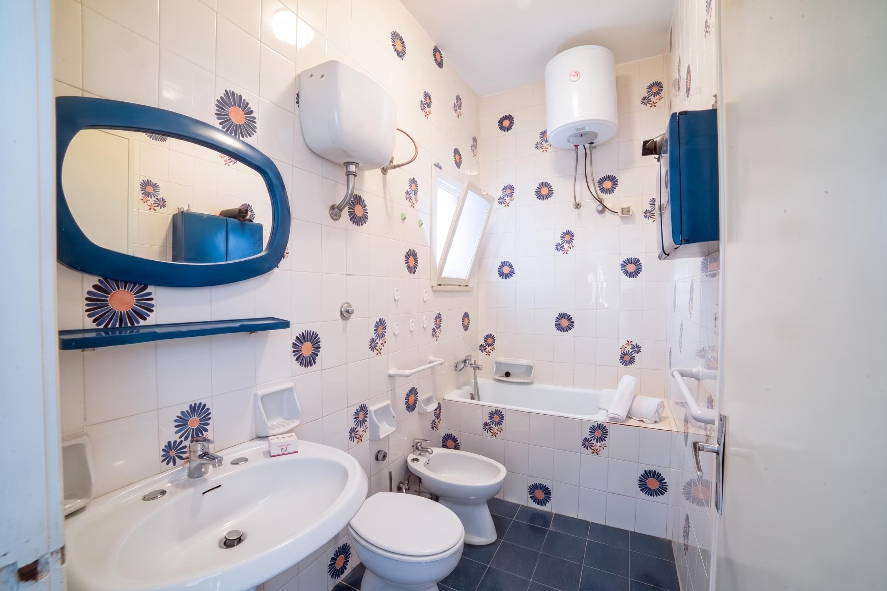 A bathroom with a sink, two toilets, a mirror, and a shower.