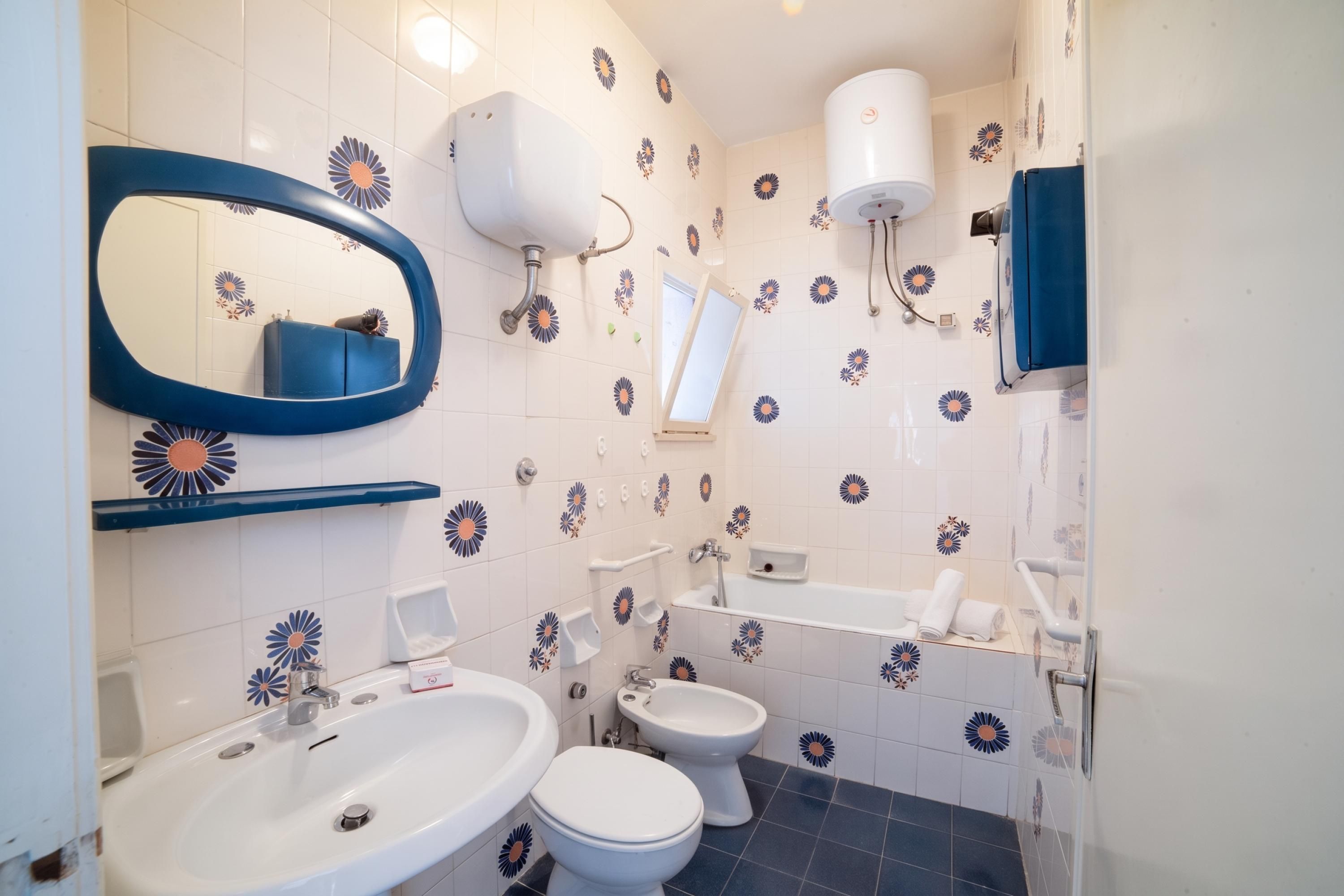 A bathroom with a sink, two toilets, a mirror, a towel rack, and a shower.