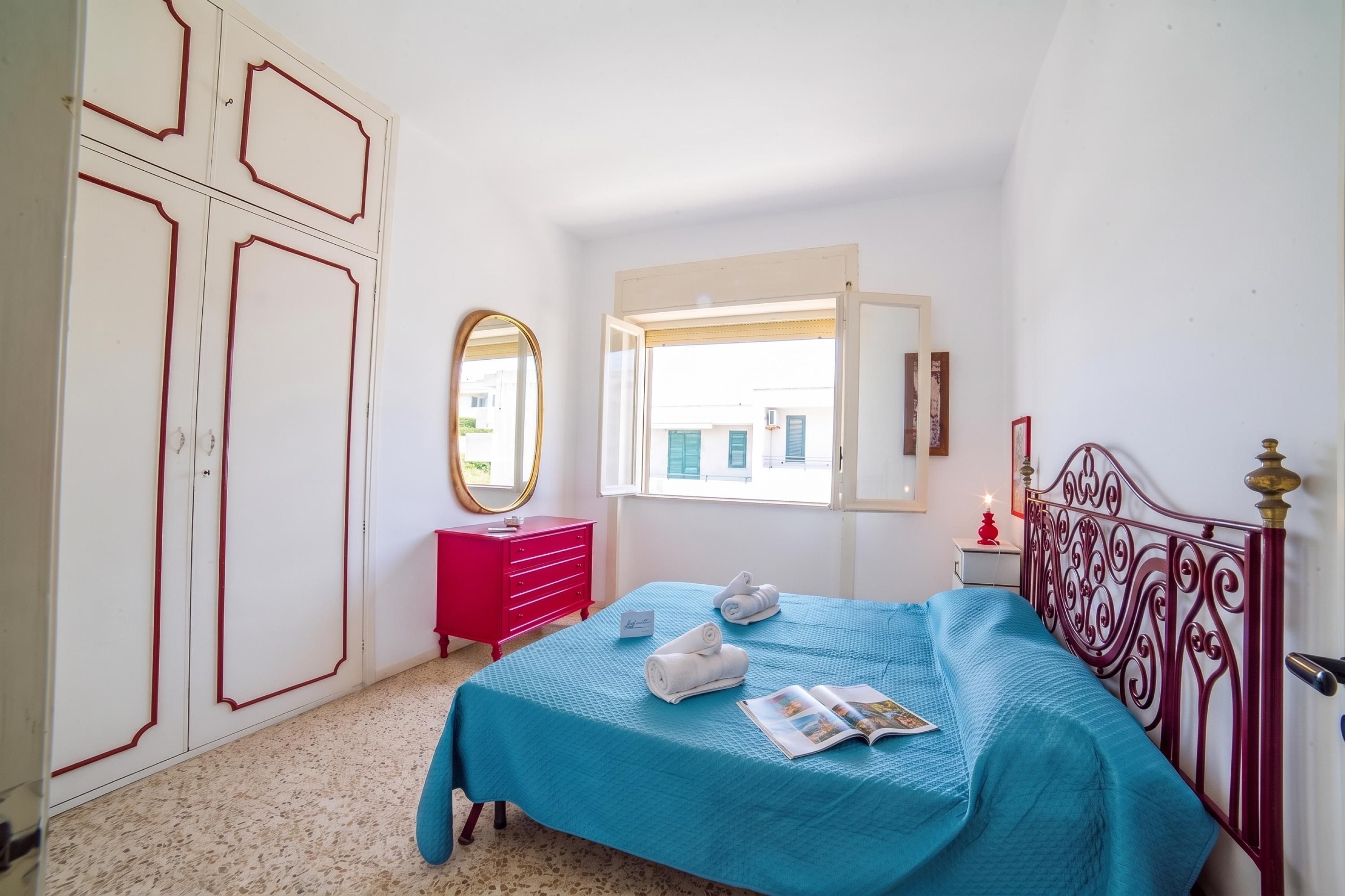 Un dormitorio con cama, cómoda, espejo y ventana.