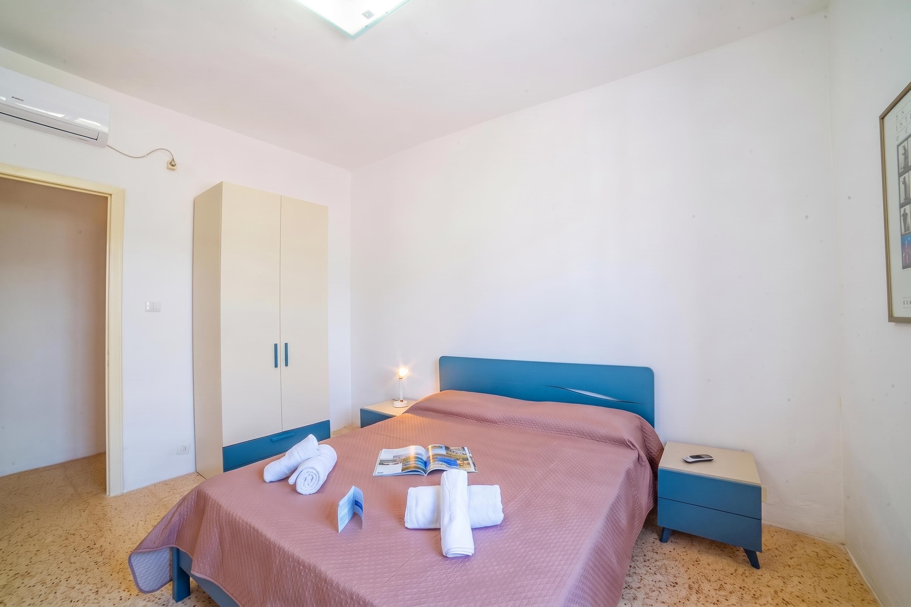 Quarto com cama, mesa de cabeceira, guarda-roupa e luminária no teto.