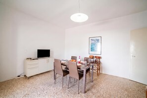 A dining area with a table set for four, a television on a cabinet, and a framed picture on the wall. - Giulia Sea View Villas (Santa Cesarea Terme)