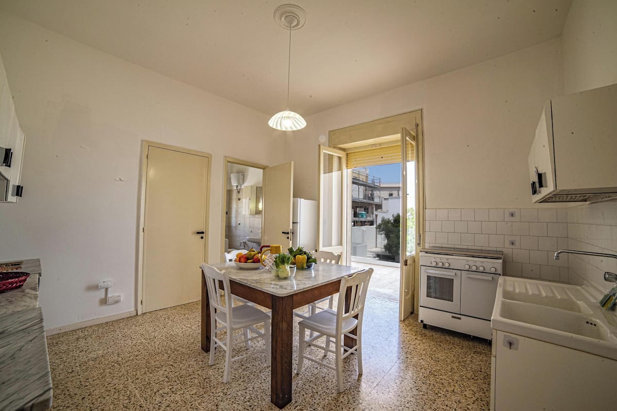 A kitchen with a dining table, chairs, a stove, and a sink.
