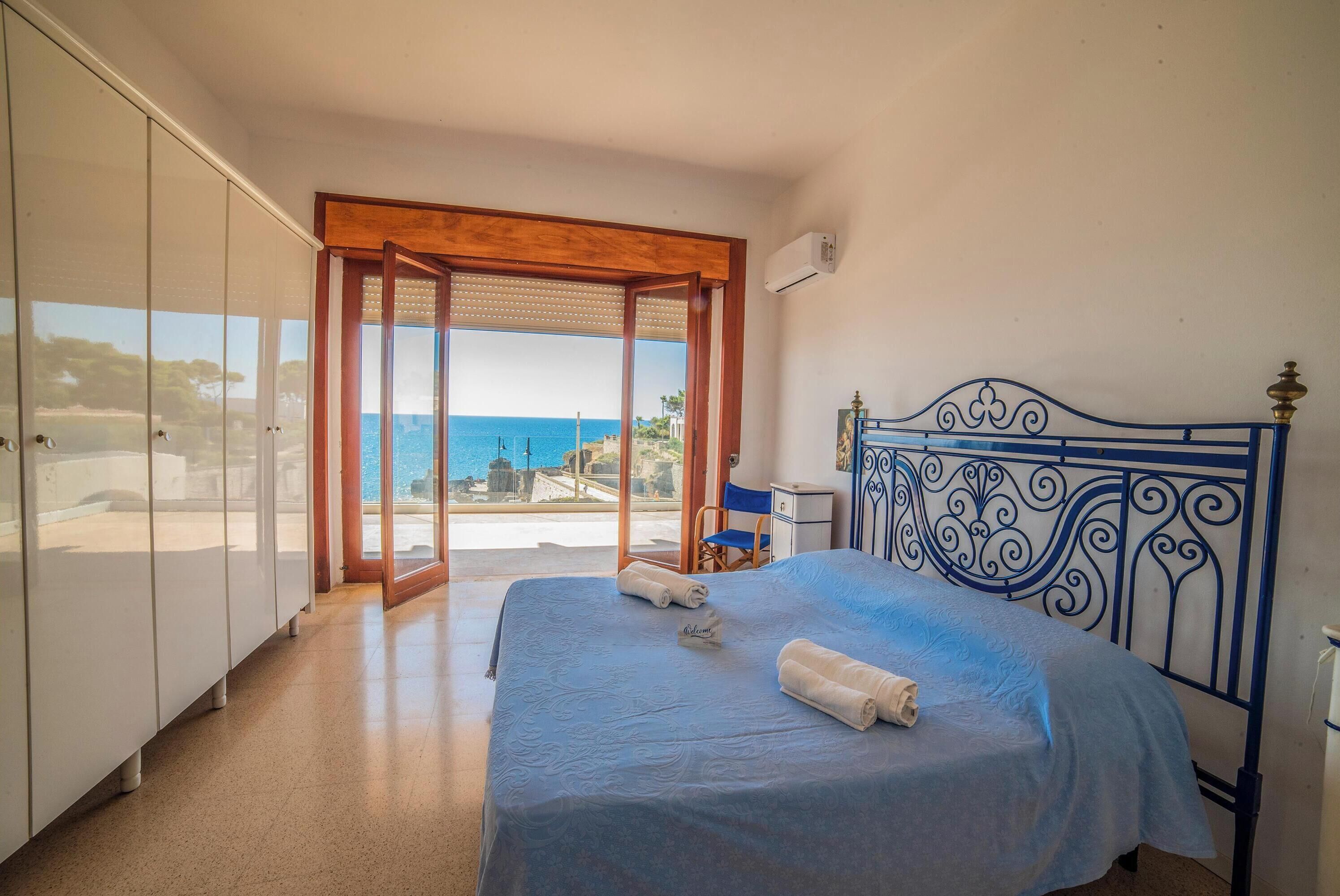 A bedroom with a bed, a wardrobe, and a view of the sea.