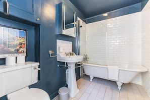 A bathroom with a white bathtub, a sink, and a toilet.