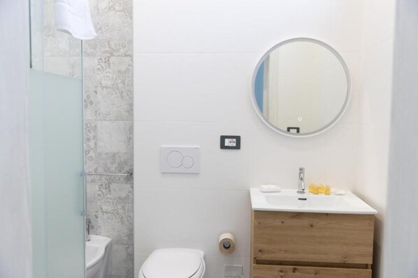 Een moderne badkamer met toilet, wastafel en spiegel.