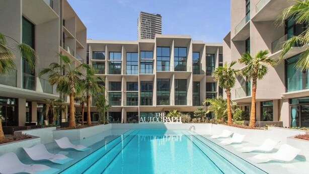 A modern building with a pool and palm trees. - Stylish 1BR Penthouse in The Autograph  (Dubai)