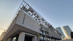 A modern building with a unique geometric facade, large windows, and a prominent entrance. - Stylish 1BR Penthouse in The Autograph  (Dubai)