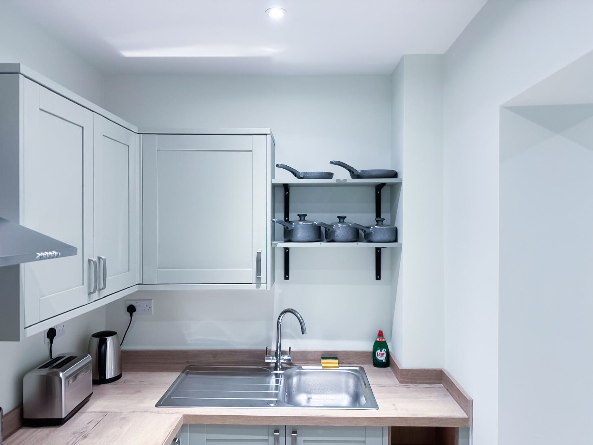 A modern kitchen with white cabinets, a stainless steel sink, and a countertop.