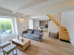 A spacious living area with a grey sofa, wooden coffee table, and a staircase leading to an upper level. - Holiday Home in Brittany Near Telgruc Beach (Telgruc-sur-Mer)