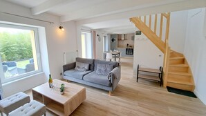 Ein geräumiger Wohnbereich mit einer Couch, einem Couchtisch und einer Treppe, die zu einer oberen Etage führt.