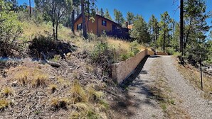 A house on a hillside with a gravel path leading to it. - Knotty Pines Cabin | Pet-Friendly, Great Location (Ruidoso)