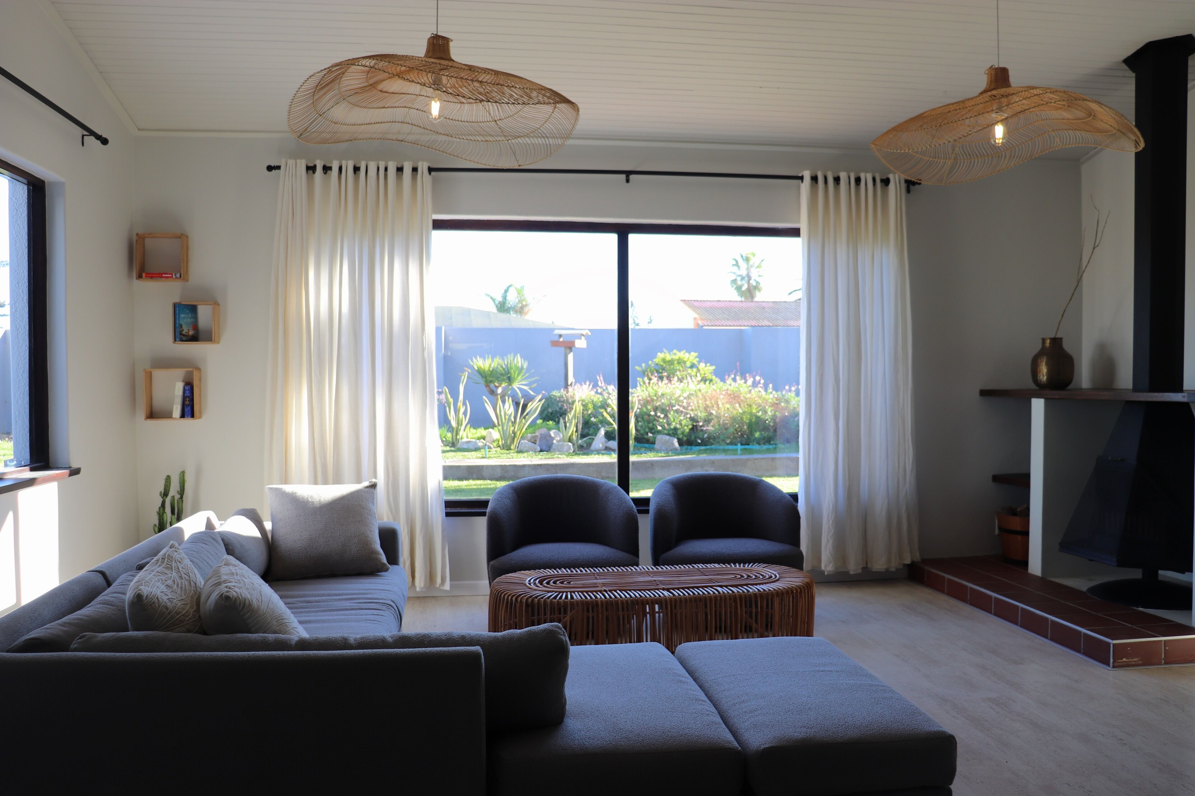 A modern living room with a sofa, two armchairs, a coffee table, and a fireplace.