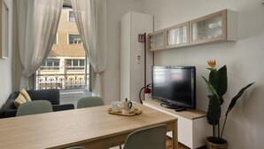 A modern living room with a television, a dining table, and a large plant. - Classy apartment near Duomo di Milano (Milan)