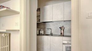 A modern kitchen with grey cabinets, a stainless steel sink, and a built-in oven. - Classy apartment near Duomo di Milano (Milan)