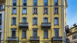 A multi-story yellow building with evenly spaced windows and balconies. - Classy apartment near Duomo di Milano (Milan)