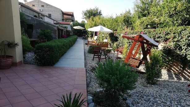 Un patio con sendero de baldosas, mobiliario exterior y plantas en macetas.