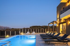 Ein Pool mit Liegestühlen und ein modernes Gebäude mit Glasfassade.